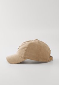 En cordfløyel caps i lys brun med seks paneler, buet skygge og justerbar lærreim med metallspenne bak.