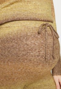 Pulôver de malha texturizada em tons degradê de amarelo a castanho. Apresenta um cordão na cintura e um tecido macio para maior conforto.