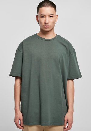 T-shirt oversized verde scuro realizzato in morbido cotone, con collo rotondo, maniche corte e dettagli di cucitura minimi.