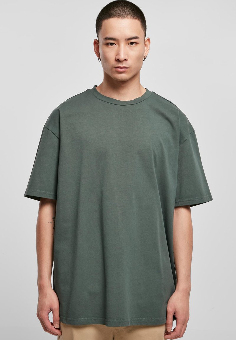 Temno zelena oversize majica iz mehkega bombaža, z okroglim ovratnikom, kratkimi rokavi in minimalnimi šivi.