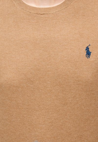 Μπεζ πλεκτό πουλόβερ με λαιμόκοψη σε στρογγυλή γραμμή και μικρό εμβληματικό λογότυπο polo σε ναυτικό μπλε στο αριστερό στήθος, με λεία υφή.