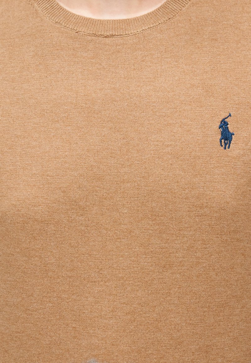 Pull beige en tricot avec un col rond et un petit logo polo bleu marine sur la poitrine gauche, texture lisse.