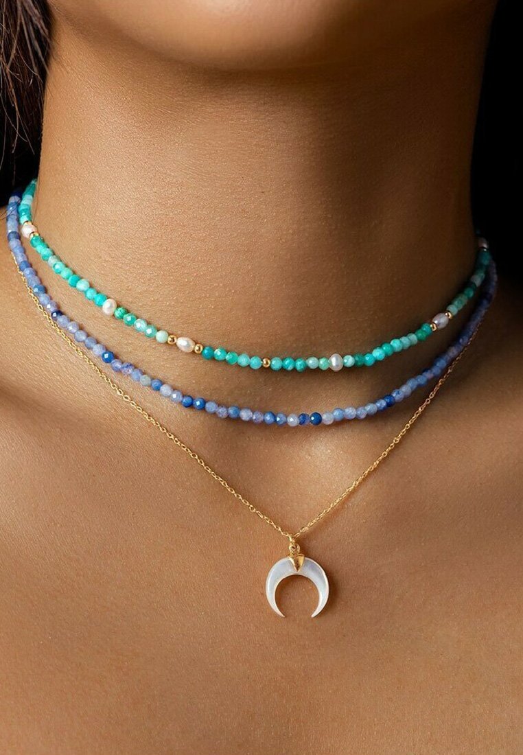 Collane a strati con perline turchesi, blu e perle, con una catena dorata e un pendente a forma di luna crescente.