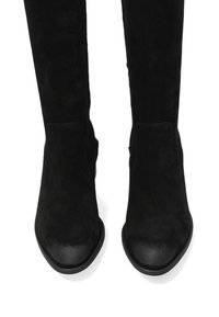 Zwarte suède kniehoge laarzen met een spitse neus en een platte rubberen zool. Subtiele stikdetails aan de zijkanten. Gladde en gestructureerde afwerking.