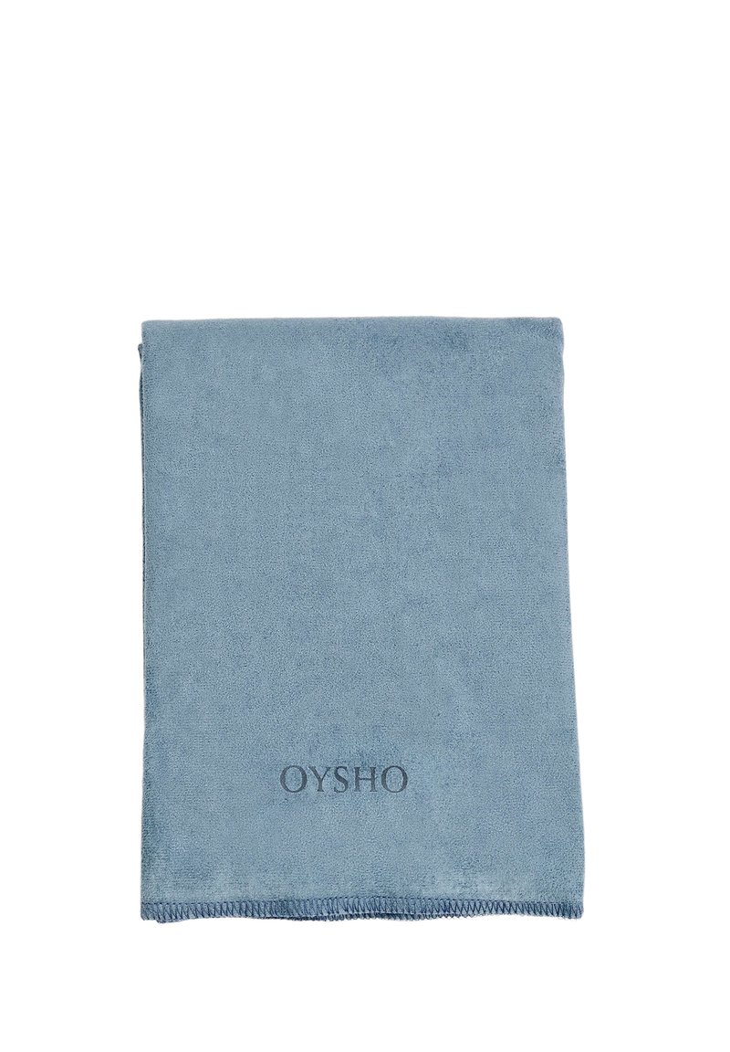 Puha kék mikroszálas törölköző, téglalap alakú, lágy textúrájú, varrott szélekkel és a bal alsó sarokban domború "OYSHO" logóval.