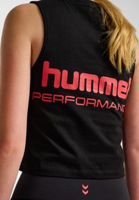 Zwarte mouwloze shirt gemaakt van zachte stof, met opvallende rode "hummel PERFORMANCE" tekst op de achterkant en een eenvoudig, relaxed fit ontwerp.