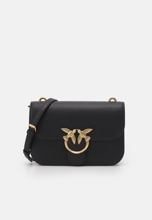 Bolso de cuero negro para el hombro con correa ajustable y cierre metálico dorado con dos pájaros detallados enfrentados.