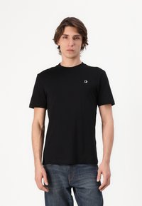 Svart bomullst-shirt med korta ärmar och rundad halsringning. Har en liten vit logotyp på vänster bröst och en avslappnad passform.