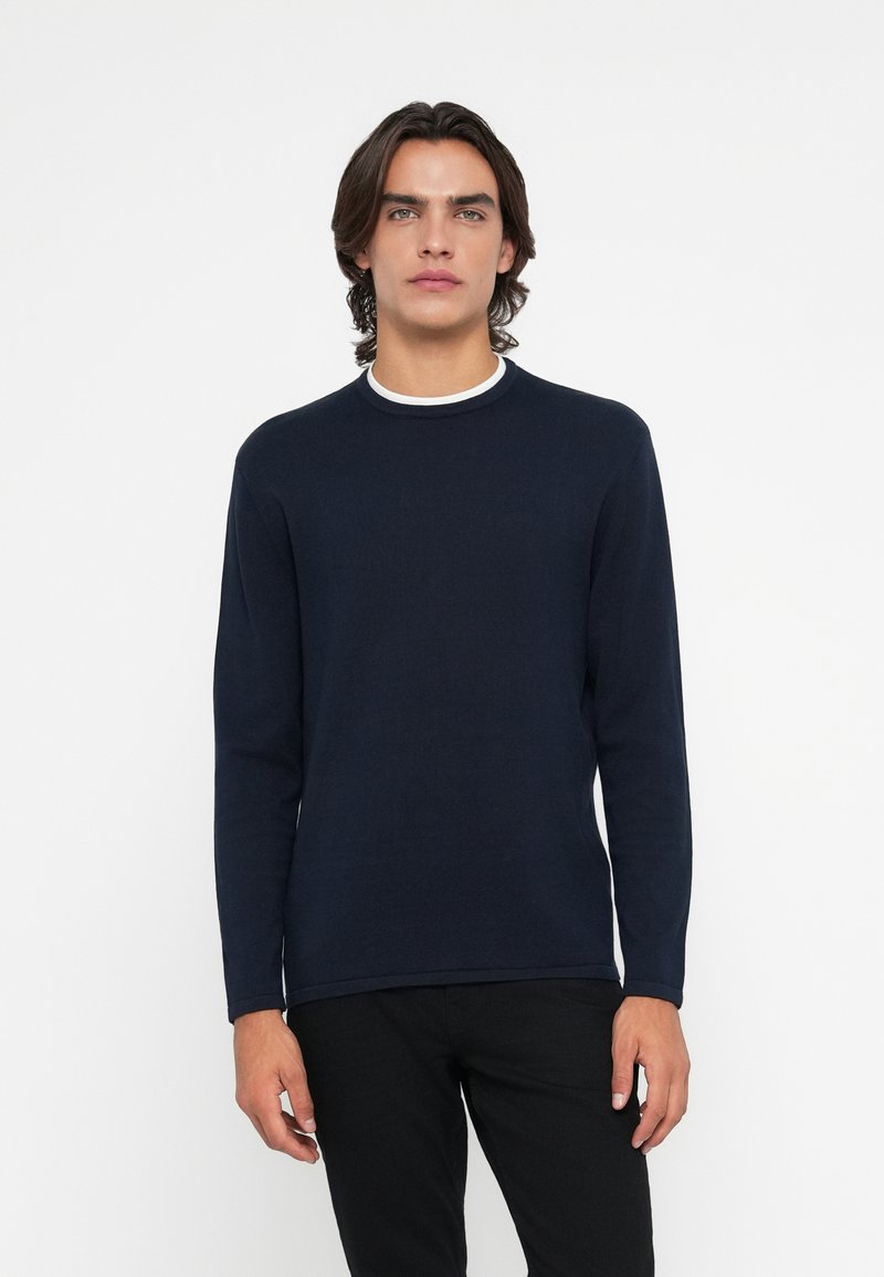 Chemise à manches longues bleu marine avec un col rond et un col à bord blanc ; fabriquée en tissu texturé, au design ajusté et de couleur unie.