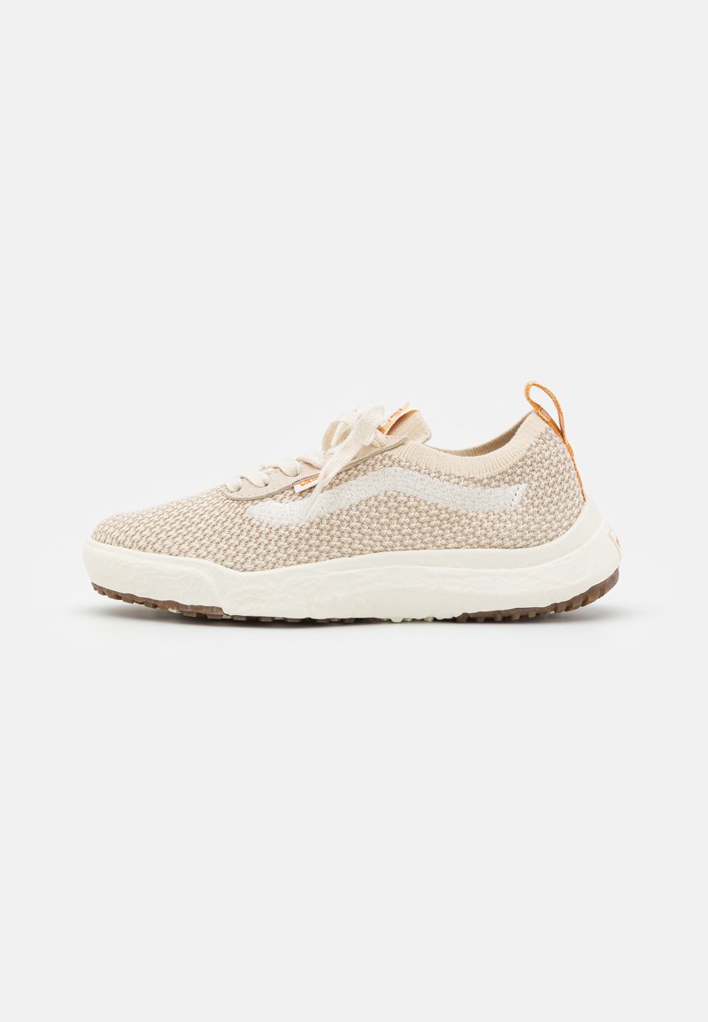 Beige knit sneakers with white accents, textured fabric, a lace-up design, and a rubber sole featuring a brown grip pattern.