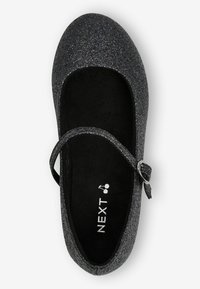 Bailarina de purpurina negra con puntera redonda, correa ajustable y plantilla de ante negro. Logotipo "NEXT" impreso en blanco en la plantilla interior.