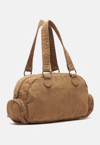 Borsa a secchiello in velluto a coste marrone con due manici robusti, scomparti con zip e estremità arrotondate. Presenta strisce testurizzate e dettagli in ottone.