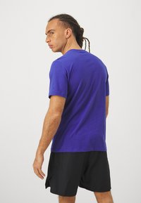 Μπλε κοντομάνικο μπλουζάκι από μαλακό ύφασμα, με στρογγυλή λαιμόκοψη και άνετη γραμμή. Φοριέται με μαύρες βερμούδες που δείχνουν έναν απλό σχεδιασμό.