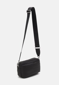 Borsa a tracolla nera in nylon morbido con chiusura a zip, design imbottito, tracolla regolabile e finiture in metallo argentato.