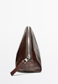 Sacoche en cuir marron avec fermeture éclair métallique, forme triangulaire et détail de poignée latérale. Texture lisse avec des accents minimaux.