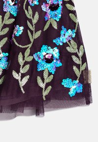 Il tessuto di tulle viola presenta motivi floreali paillettati in blu e verde con centri neri. Hardware decorativo dorato su un lato.