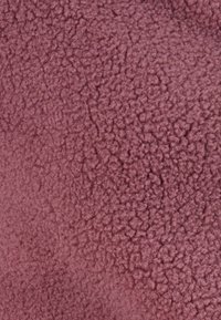 Texture di tessuto malva con un aspetto morbido e soffice. La superficie presenta un pelo denso con un motivo leggermente irregolare.