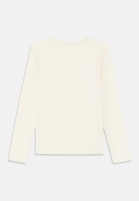 Dlhý rukáv, jednoduchá off-white košeľa s okrúhlym výstrihom, zobrazená zozadu na svetlom pozadí.