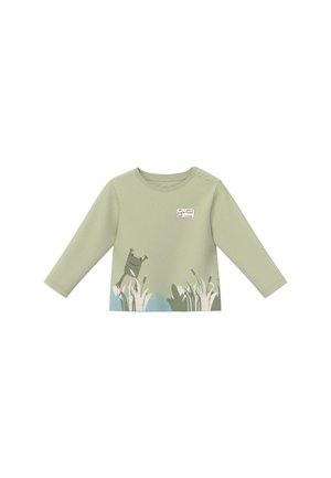 Jasnozielona koszulka z długim rękawem dla malucha z wzorem żaby i trawy oraz naszywką "nie martw się, bądź szczęśliwy" na piersi.