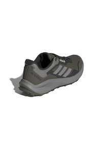 Baskets de sport grises avec une tige texturée, ornées de rayures blanches et d'un talon renforcé. La semelle extérieure est conçue pour offrir une bonne adhérence.