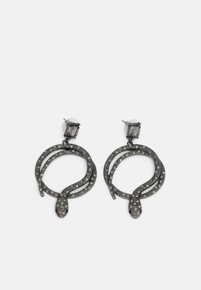 Paire de boucles d'oreilles en strass noir en forme de serpents enroulés, chacune ornée d'un clou rectangulaire facetté sur le dessus, sur fond uni.