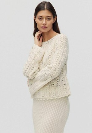 Cremfarbener gestrickter Pullover mit einem strukturierten Muster, Rundhalsausschnitt und gerippten Bündchen. Der gewellte Saum verleiht dem Design eine schöne Note.