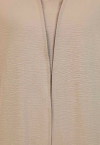 Cardigan beige chiaro con una texture liscia, design aperto davanti e pieghe sottili, con un taglio dritto lungo i bordi.