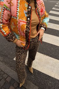 Gequiltte, multicolore jas met dierenprint, gecombineerd met strakke luipaardbroeken. Een beige top en puntige beige hakken maken de outfit compleet.