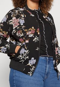 Blommig bomberjacka i svart med färgglada blommor. Ribbad ärm och nederkant, lättviktigt tyg och dragkedja framtill.