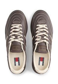 Brązowe skórzane trampki z białym przeszyciem i sznurowadłami. Posiadają naszywkę z logo na języku oraz teksturowaną gumową podeszwę.