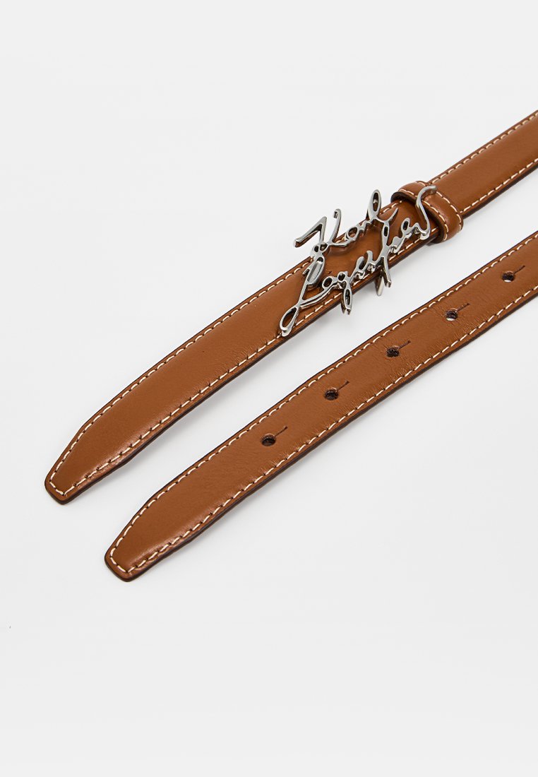 Ceinture en cuir brun avec une boucle en métal argenté. Présente des détails de couture et plusieurs trous d'ajustement le long de la sangle.