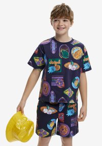 Purple short-sleeve t-shirt and matching shorts with colorful graphic prints. Lightweight fabric, relaxed fit, and a yellow shiny hat held in hand.