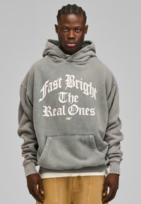 Grå oversized hoodie med hvid grafisk tekst, der læser "Fast Bright The Real Ones," med en kængurulomme og ribbede manchetter.