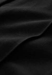 Black textured fabric featuring a smooth finish and subtle ribbing, with overlapping folds creating depth and dimension.
