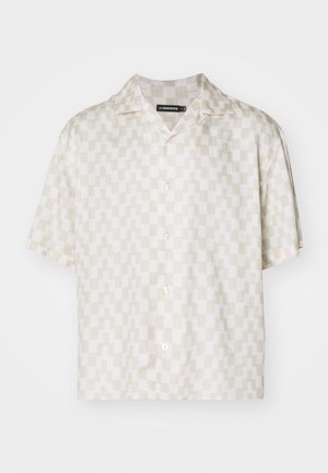 Chemise à manches courtes avec un motif géométrique crème et beige, tissu léger, col en V et cinq boutons sur le devant.