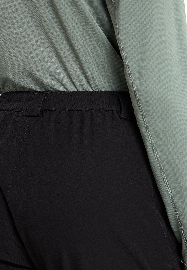 Zielona bluzka z długim rękawem o teksturowanej tkaninie oraz czarne spodnie z elastycznym paskiem w talii. Ubranie charakteryzuje się gładkim wykończeniem i wygodnym dopasowaniem.