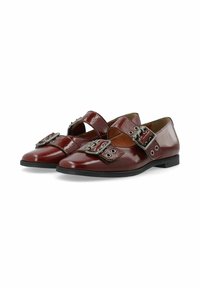 Burgunderfarbene Lacklederschuhe mit spitzer Zehenpartie, die mit einem breiten Riemen und einer großen silbernen Schnalle akzentuiert sind. Flache Sohle und glatte Textur.