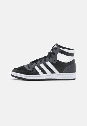 Czarno-szare sneakersy za kostkę z białymi paskami Adidas i białą podeszwą, pokazane z profilu na jednolitym białym tle.