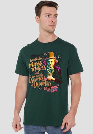 Man wearing dark green Willy Wonka t-shirt with colorful text "We are the Music Makers and We are the Dreamers of Dreams" and character illustration.