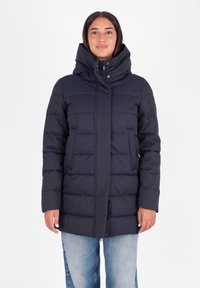 Donkerblauwe, geïsoleerde pufferjas met een hoge kraag, ritssluiting en twee voorzakken. Textuur in een geborduurde quiltpatroon voegt dimensie toe.