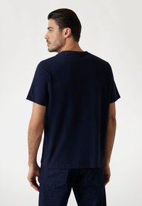 Mørkeblå kortærmet t-shirt lavet af blødt stof med rund halsudskæring, der har en afslappet pasform og et enkelt design uden mønstre eller dekorationer.