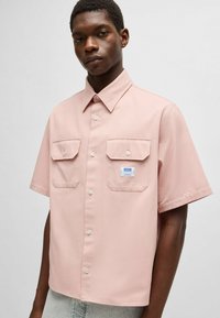 Korte mouwen roze shirt met een button-down kraag, twee borstzakken en een klein merklabel. Glad materiaal met een gestructureerde vorm.