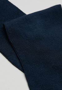 Dunkelblaue gerippte Socken mit glatter Textur und elastischem Bund, die eine subtile Dehnbarkeit für einen bequemen Sitz und Langlebigkeit bieten.