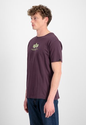 Lila Crewneck-T-Shirt mit einem grünen Grafiklogo auf der Brust, kurzen Ärmeln und einer lockeren Passform, hergestellt aus weichem Baumwollmaterial.