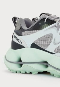 Baskets de sport pour hommes avec une tige en maille grise et des accents blancs, une semelle mint verte rembourrée et des détails texturés noirs.