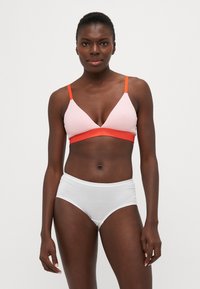 Bralette rose clair avec des bretelles orange, présentant un design triangular et une large bande orange. Associé à des culottes blanches taille haute.