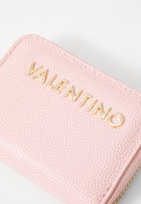 Portefeuille en cuir texturé rose avec lettrage doré "VALENTINO", doté d'une fermeture zippée et de détails de couture visibles.