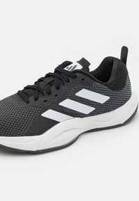 Schwarzer Sportschuh mit Mesh-Obermaterial, weißem Dreistreifen-Design, gepolstertem Kragen, Schnürverschluss und einer weißen Zwischensohle mit strukturierten Details.