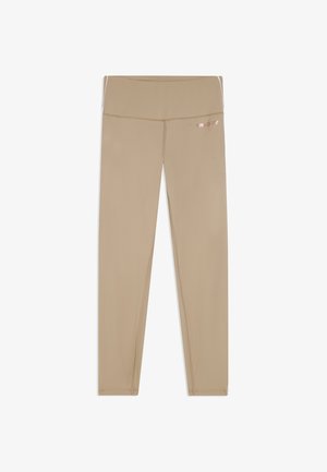 Leggings beige de cintura alta para mujer con costuras visibles y pequeño logo reflectante en la cadera derecha, mostrados planos sobre un fondo blanco.