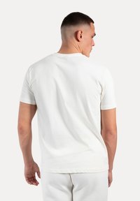 Hvid bomulds T-shirt med korte ærmer og rund hals. Glat tekstur med et simpelt design, der viser en afslappet pasform bagpå.